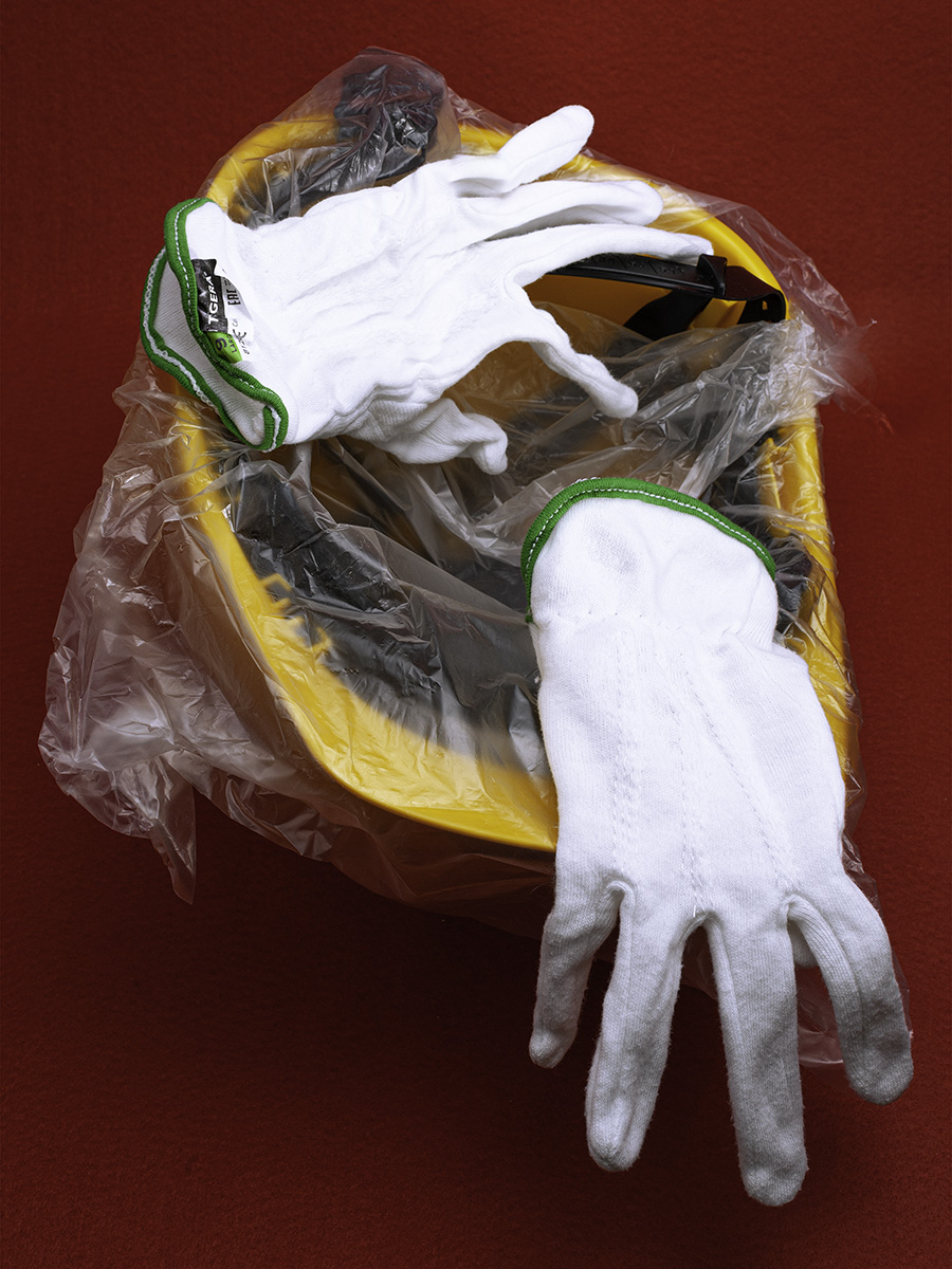 Un casco da lavoro giallo con 2 guanti bianchi su sfondo rosso