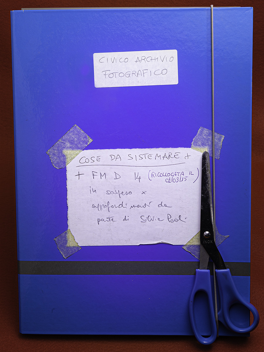 Una cartella blu con scritto sopra cose da sistemare, con delle forbici