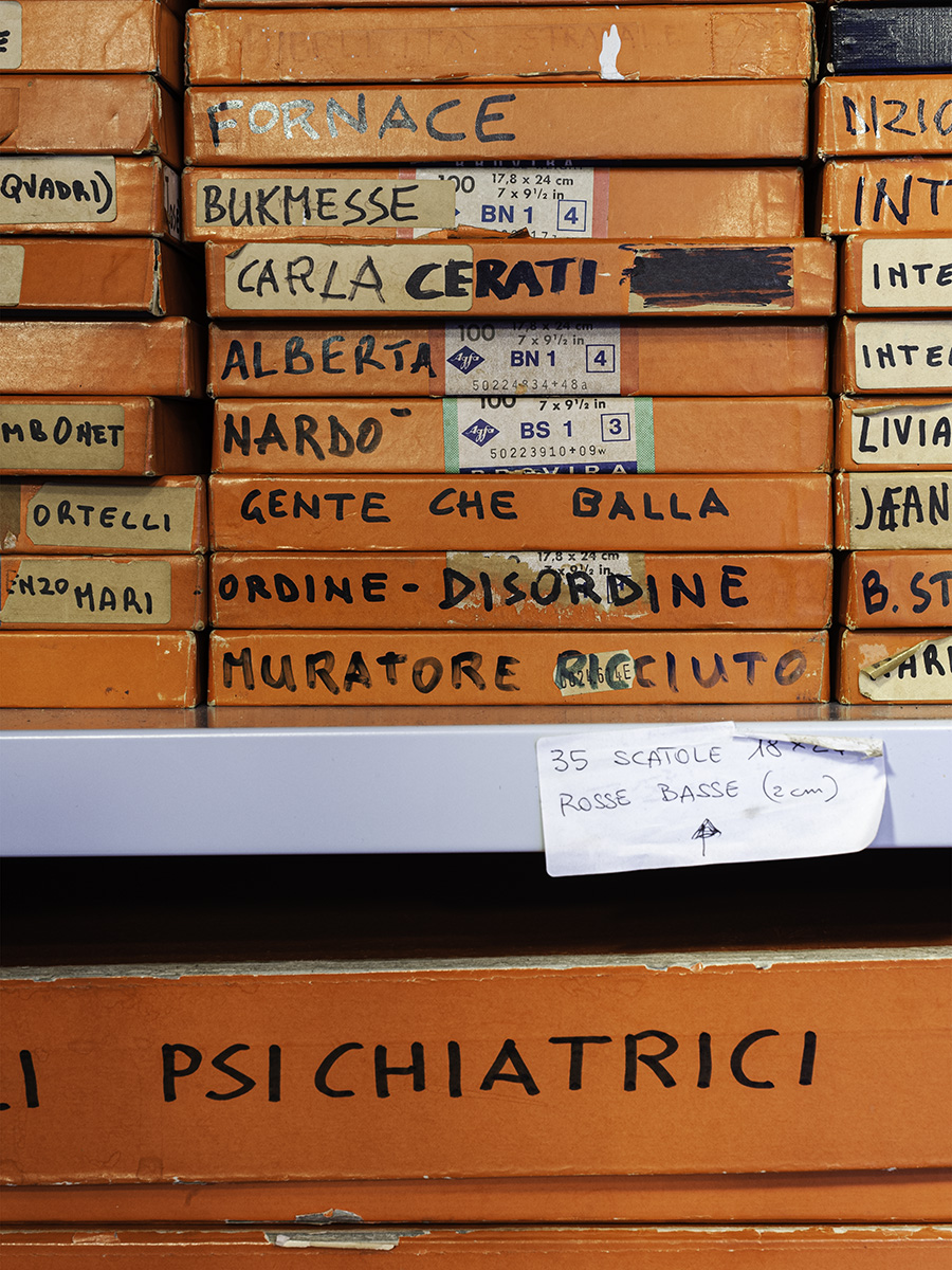Un armadio aperto contenente scatole di cartone arancioni per l'archiviazione di immagini, le scatole hanno scritto sopra il contenuto