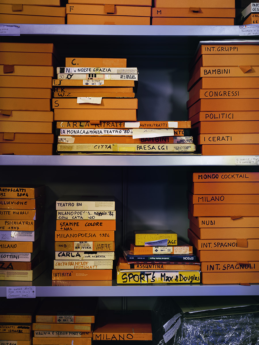 Un armadio aperto contenente scatole di cartone arancioni per l'archiviazione di immagini, le scatole hanno scritto sopra il contenuto
